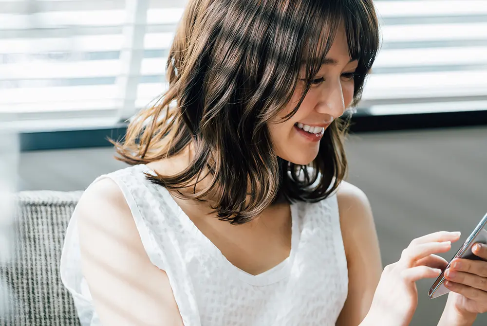 スマートフォンを手に取り、通知を確認している女性。