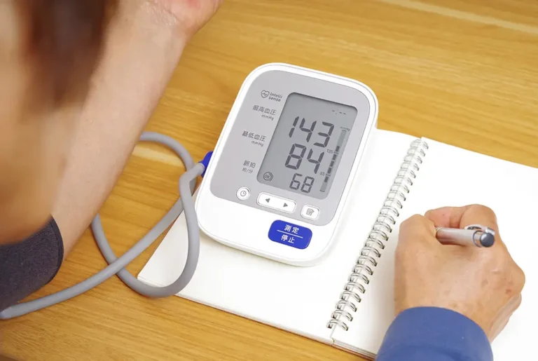 家庭用血圧計で測定した数値をノートに記録している様子。