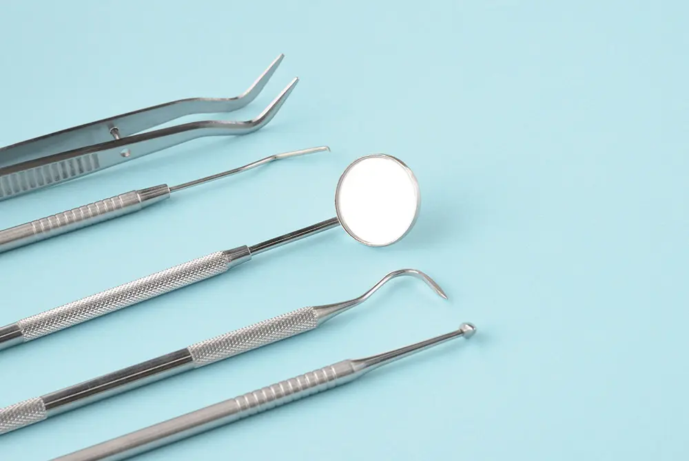 デンタルミラーやピンセットなどの歯科用器具が並べられている様子。