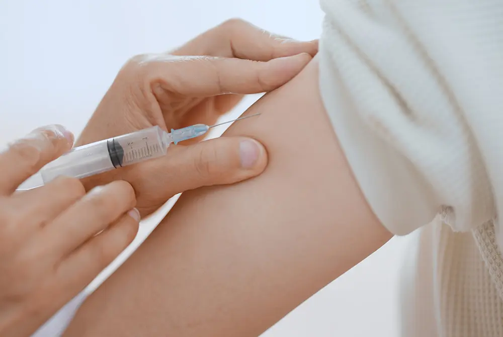 医療従事者が上腕に注射を行っている様子。