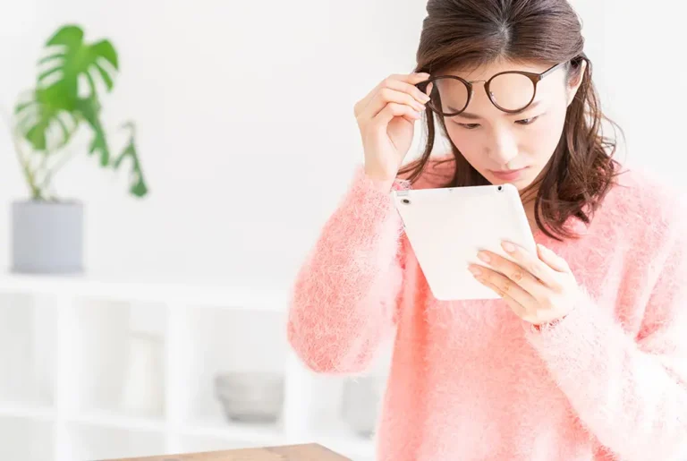 眼鏡を額に上げ、タブレットを見つめる女性。