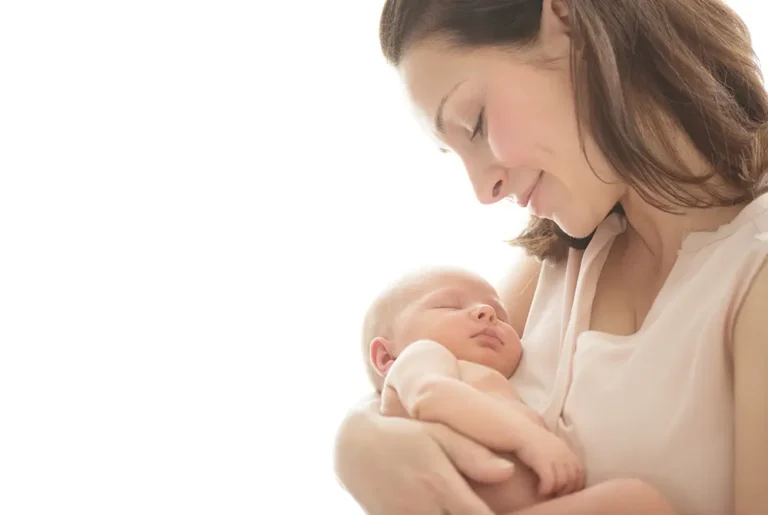 母親が新生児を優しく抱いて見つめている様子。