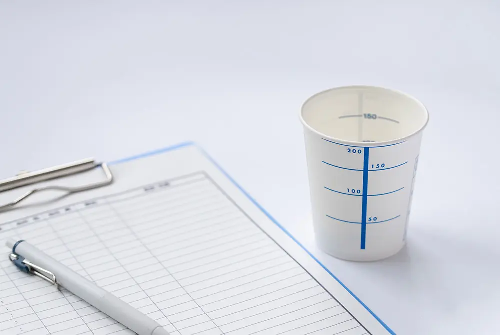 尿検査用の紙カップと問診票、ボールペン。