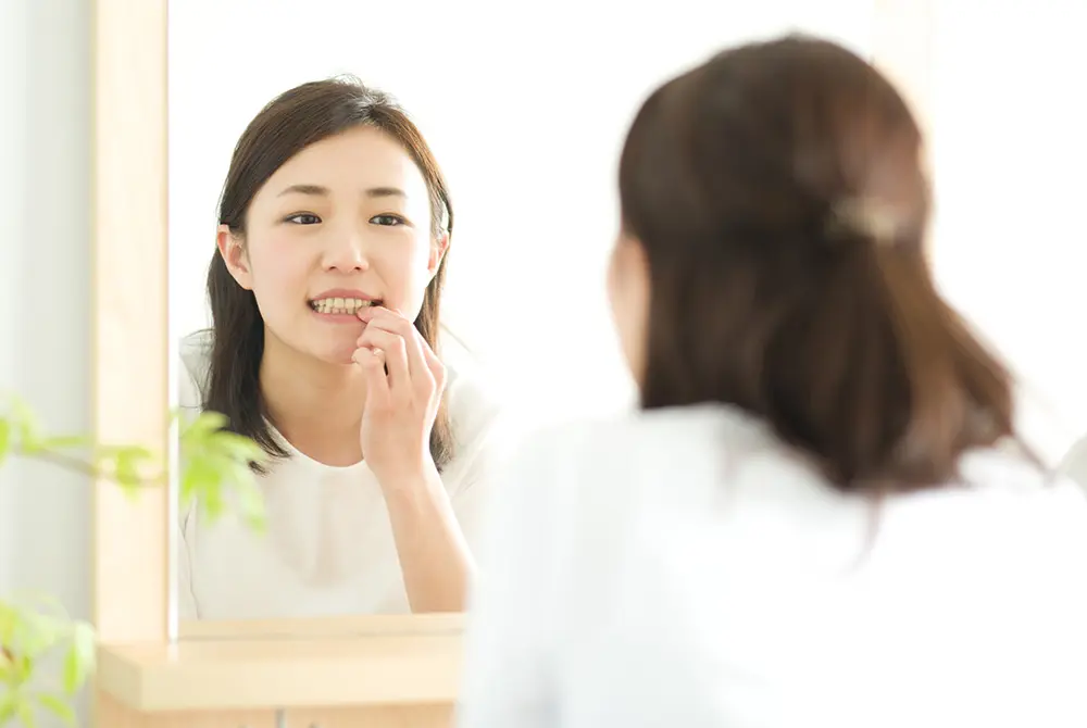 鏡を見ながら歯の状態を確認する女性