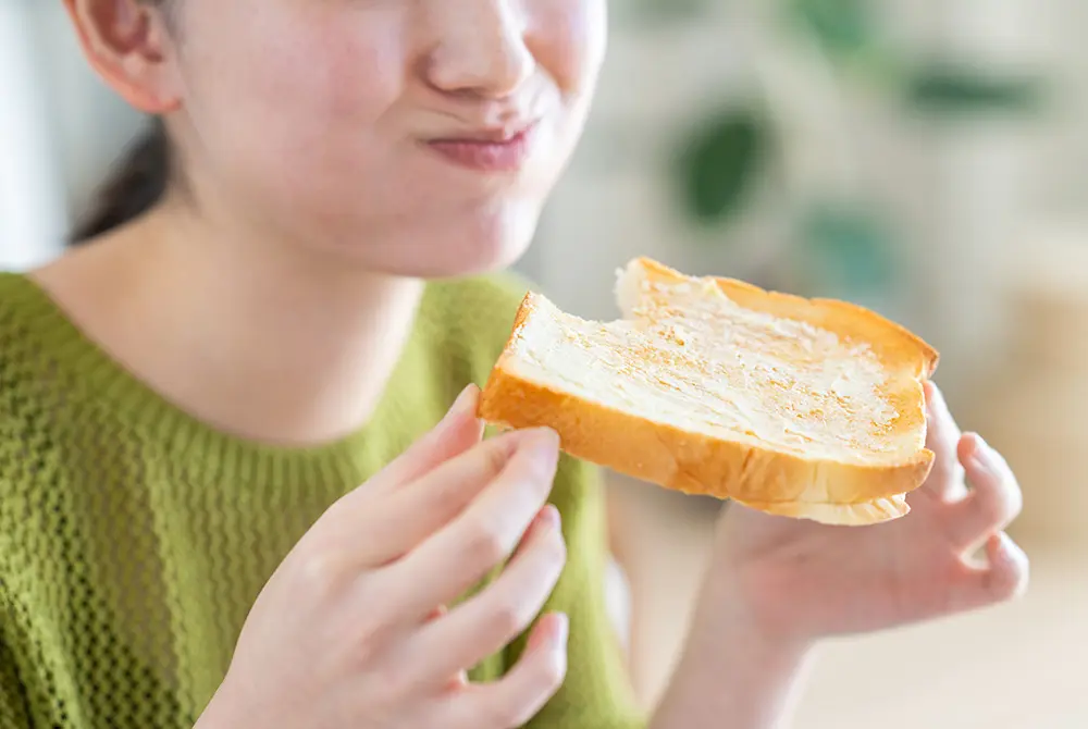 食パンを手に持って食べる女性