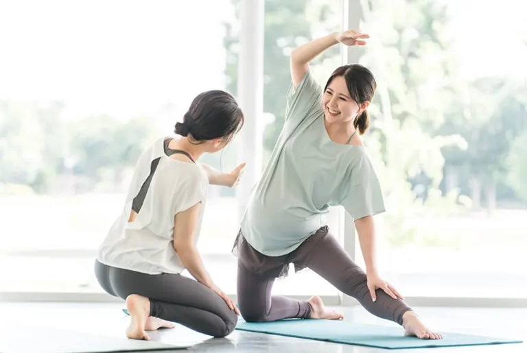 指導者とともにストレッチを行う妊婦