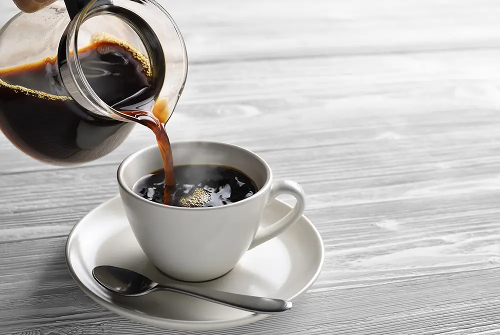 ポットからカップにコーヒーを注ぐ様子