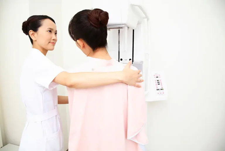 医療スタッフに誘導されマンモグラフィ検査を受ける女性