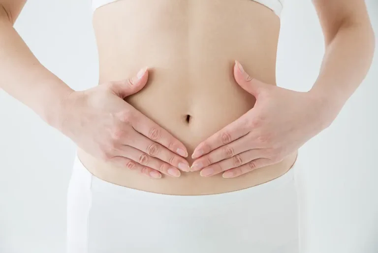 手で下腹部を押さえる女性の腹部