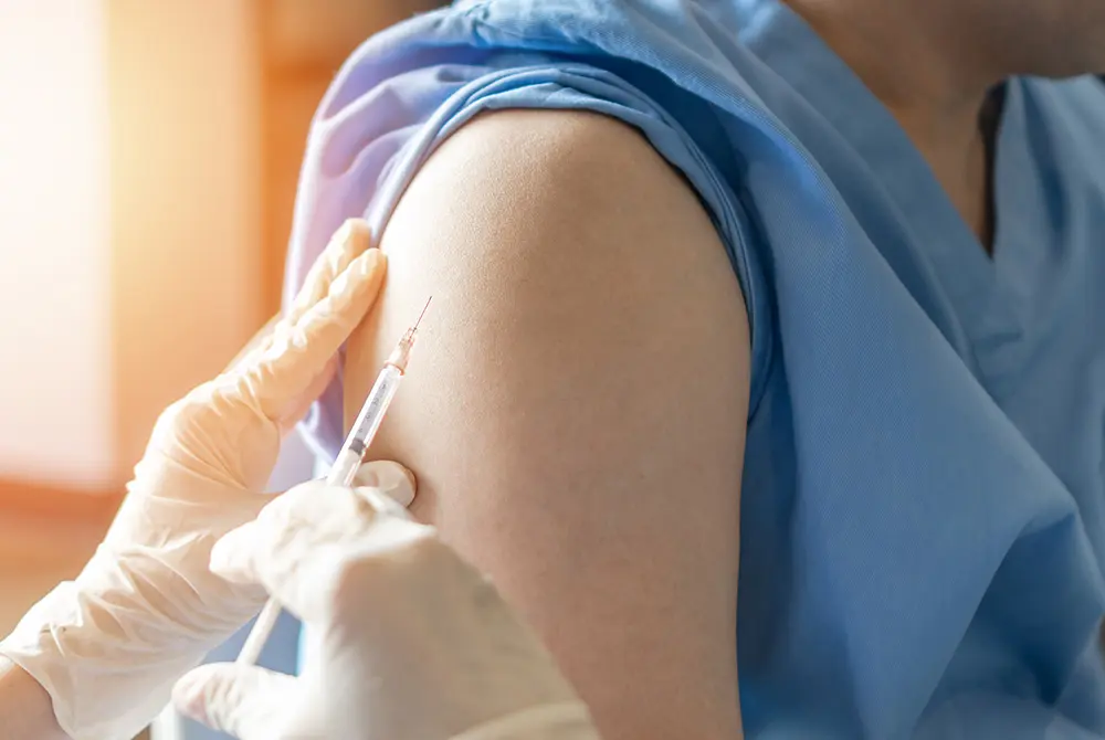 上腕に注射針を刺してワクチンを接種する手元のアップ