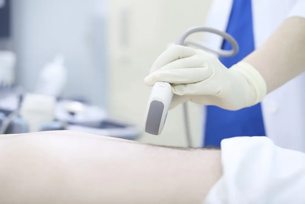 医療従事者がプローブを当てて腹部の超音波検査を行う様子