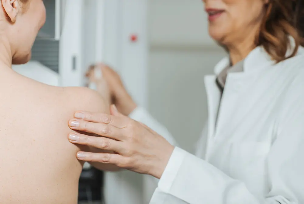 医師が患者の上半身に手を添えて乳房の状態を確認する様子