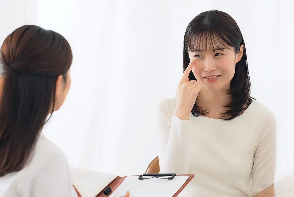 目元を指さしながら症状を相談する女性