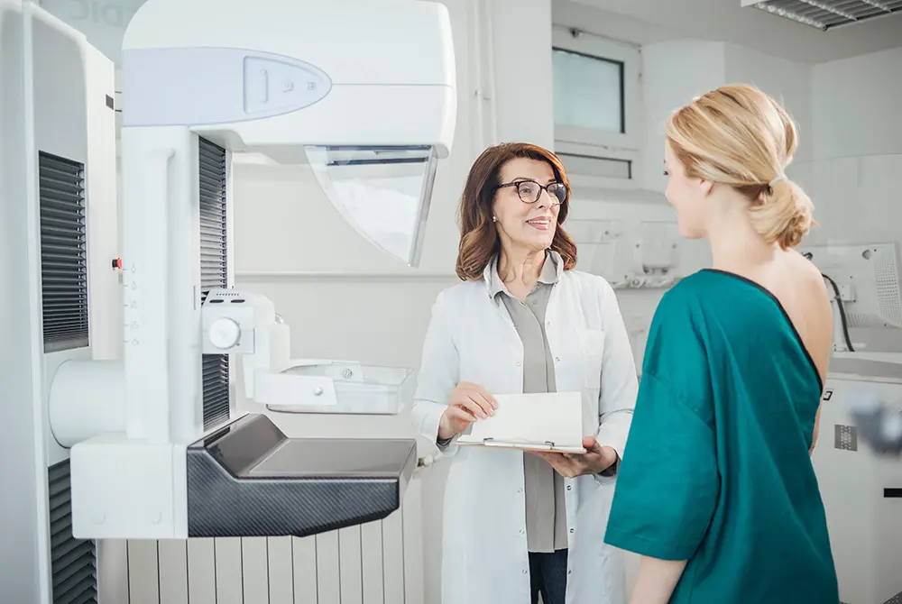 マンモグラフィ装置の前で医療者が患者に説明している様子