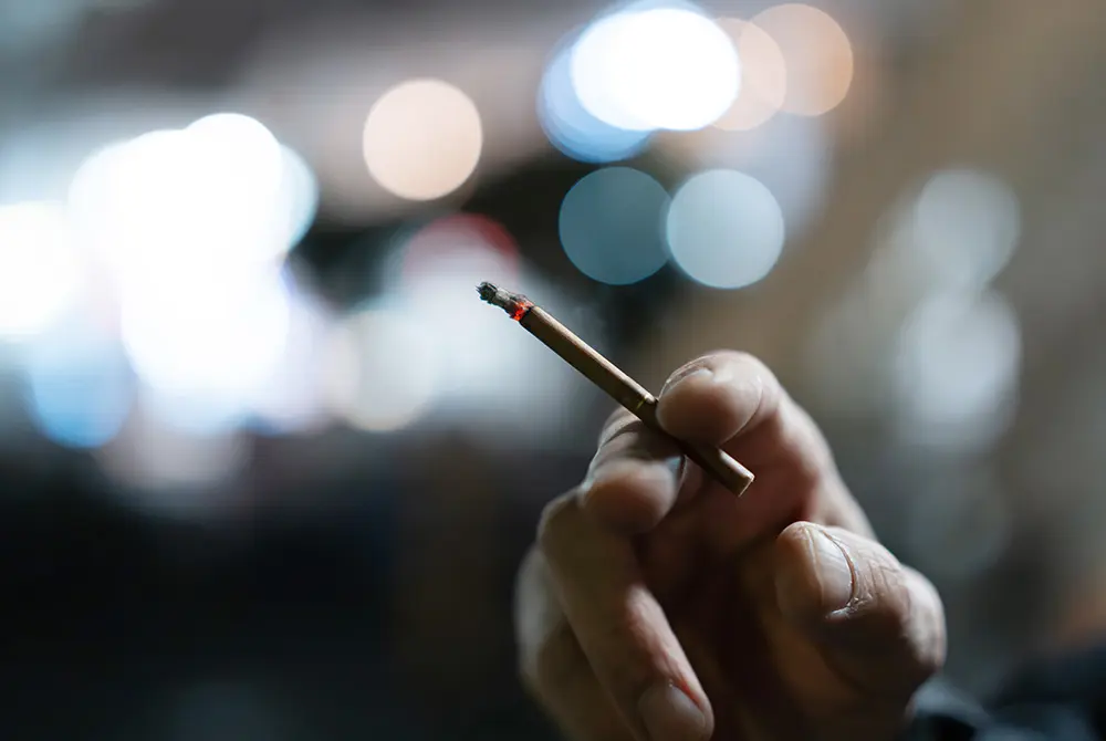 手に持った紙巻きたばこの先端が燃えている様子