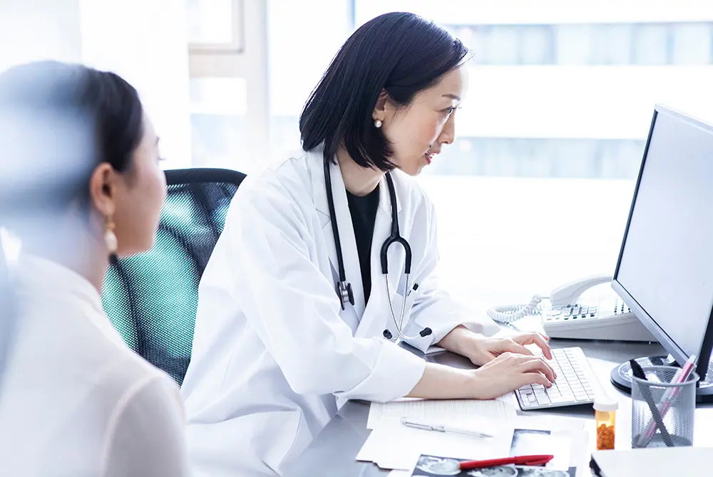 医師がパソコンを操作しながら患者の情報を確認している様子