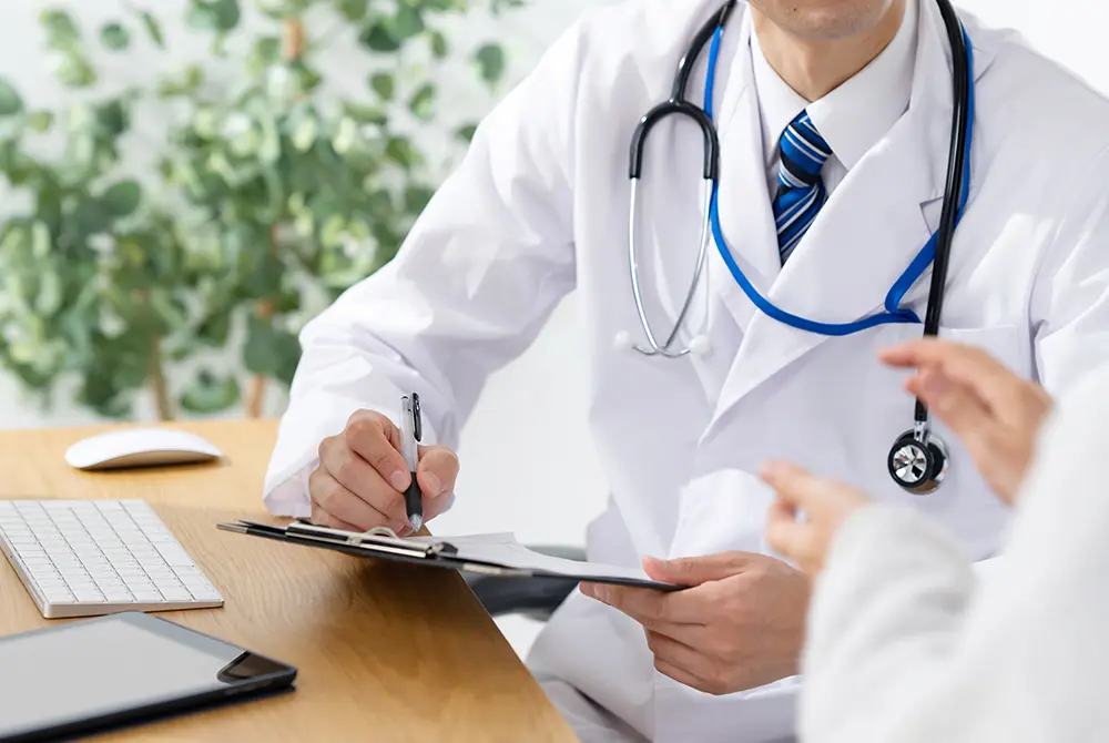 医師が患者の話を聞きながら問診票に記入している様子