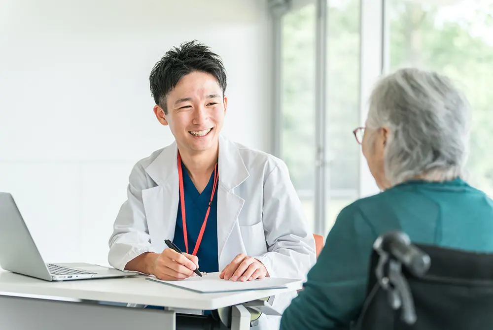 医師が高齢の患者と笑顔で対話しながら診察する様子