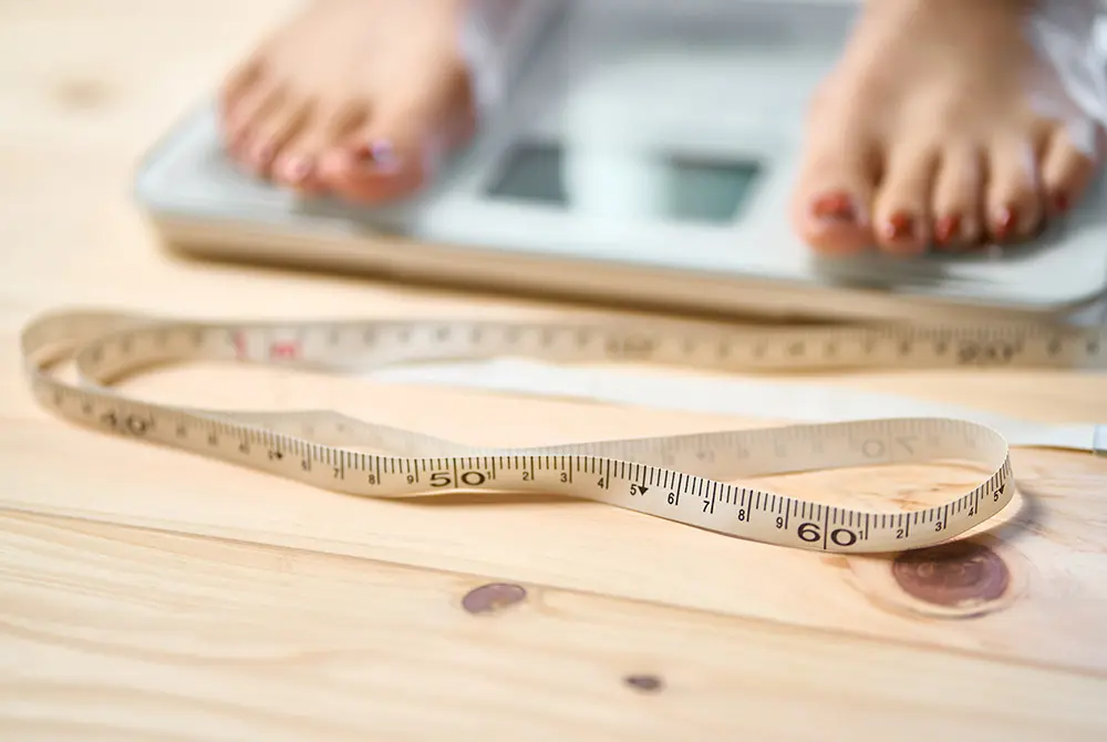 体重計の手前にメジャーが置かれ、奥に足が乗っている様子