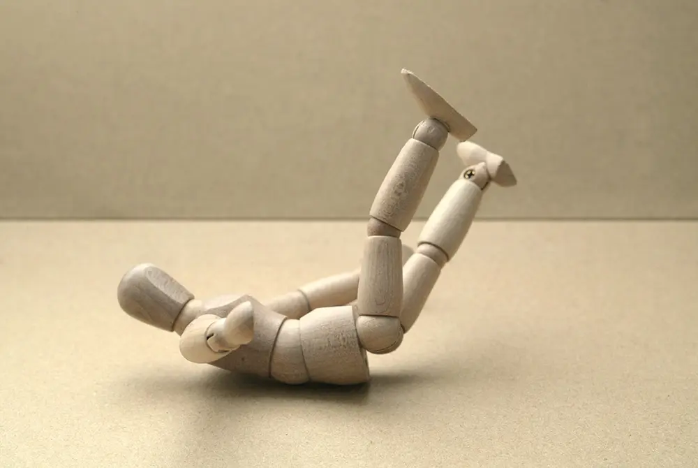 木製の人体模型が仰向けで脚を上げている様子