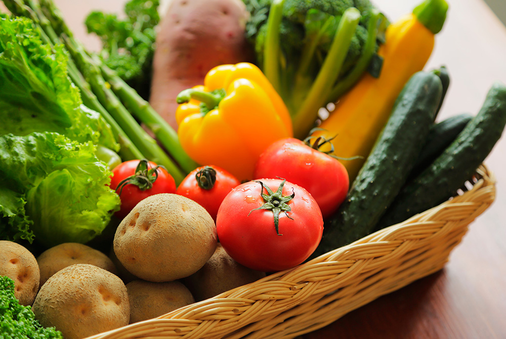 かごに盛られたトマトやパプリカ、葉物野菜などの新鮮な野菜