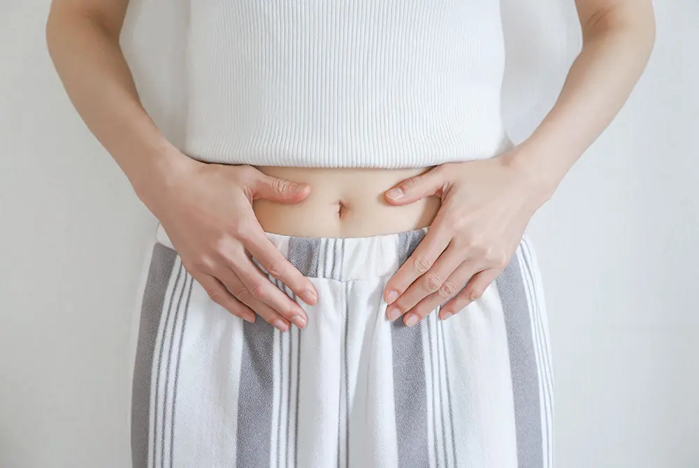 下腹部に手を当てる女性の様子