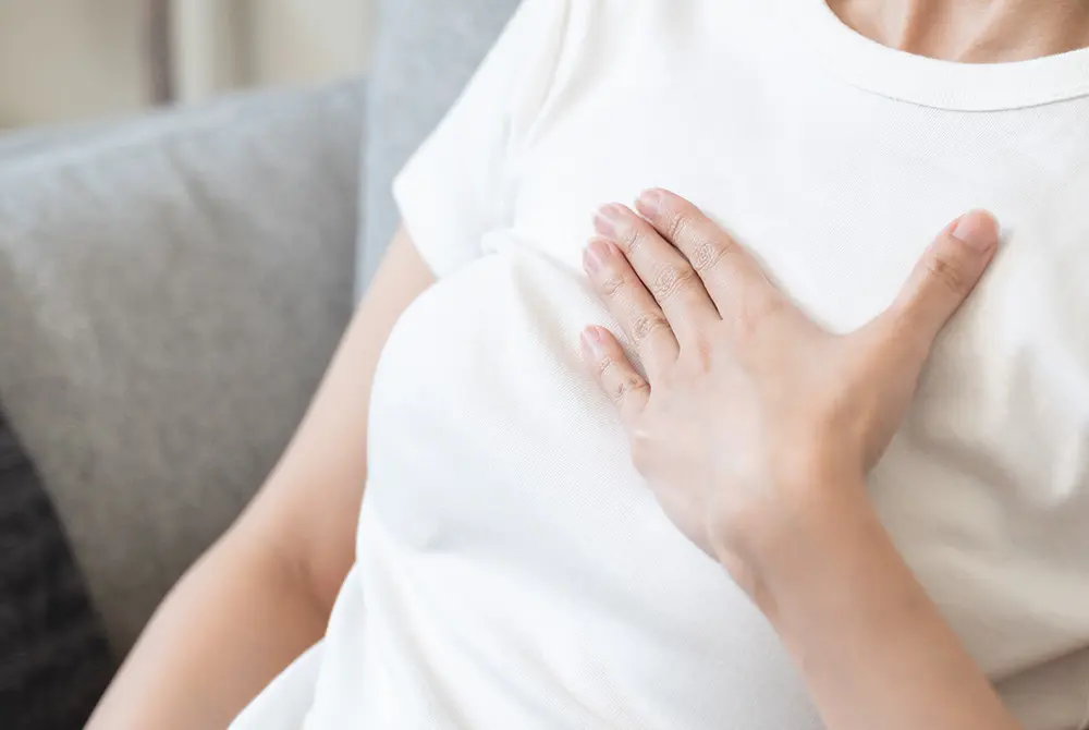 胸に手を当てて違和感を感じている女性