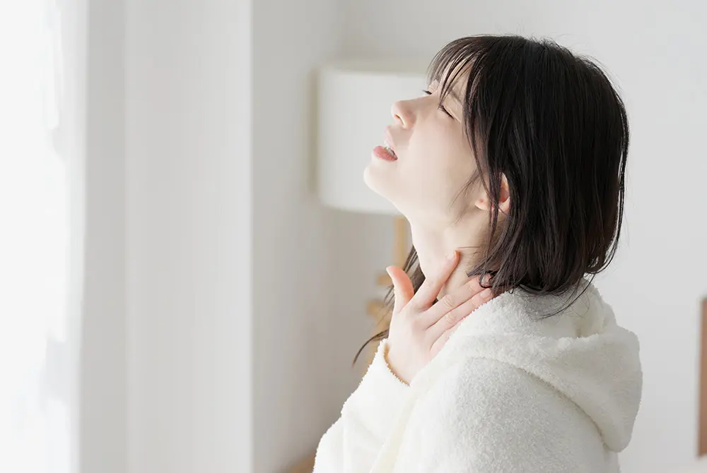 首に手を当てて不調を感じている女性