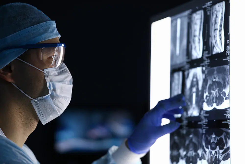 医療従事者が防護メガネとマスクを着用し、画像診断フィルムを確認している様子。