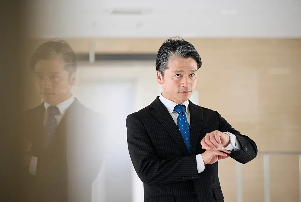 スーツ姿の男性が腕時計を確認している様子。