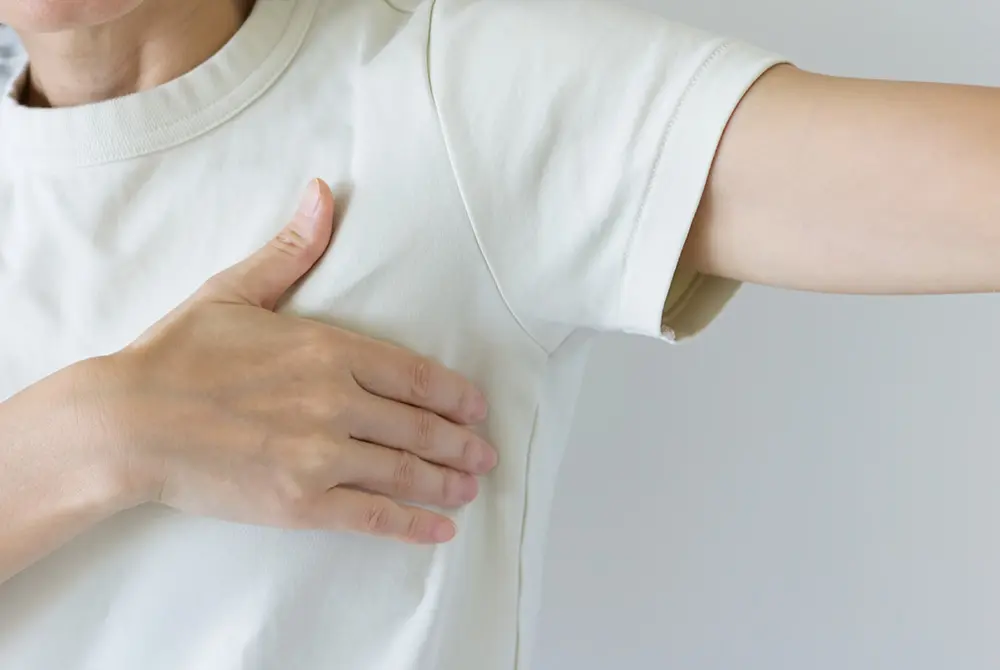 脇の下に手を当てる人の上半身。わきの違和感やしこりの確認を示すイメージ。