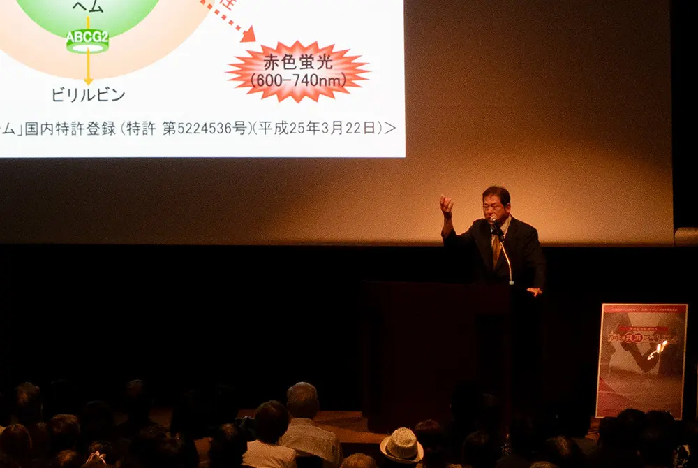 講演会でマイクを前に話す井上啓史氏。