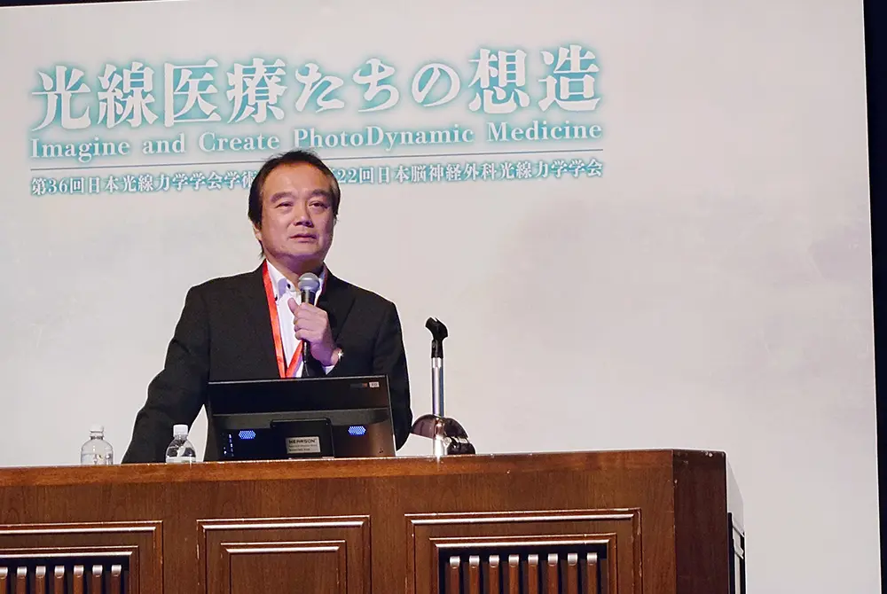 マイクを手に、第36回日本光線力学学会学術講演会で講演する小倉俊一郎氏。