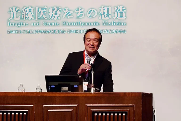 第36回日本光線力学学会学術講演会で、笑顔でマイクを持つ小倉俊一郎氏。