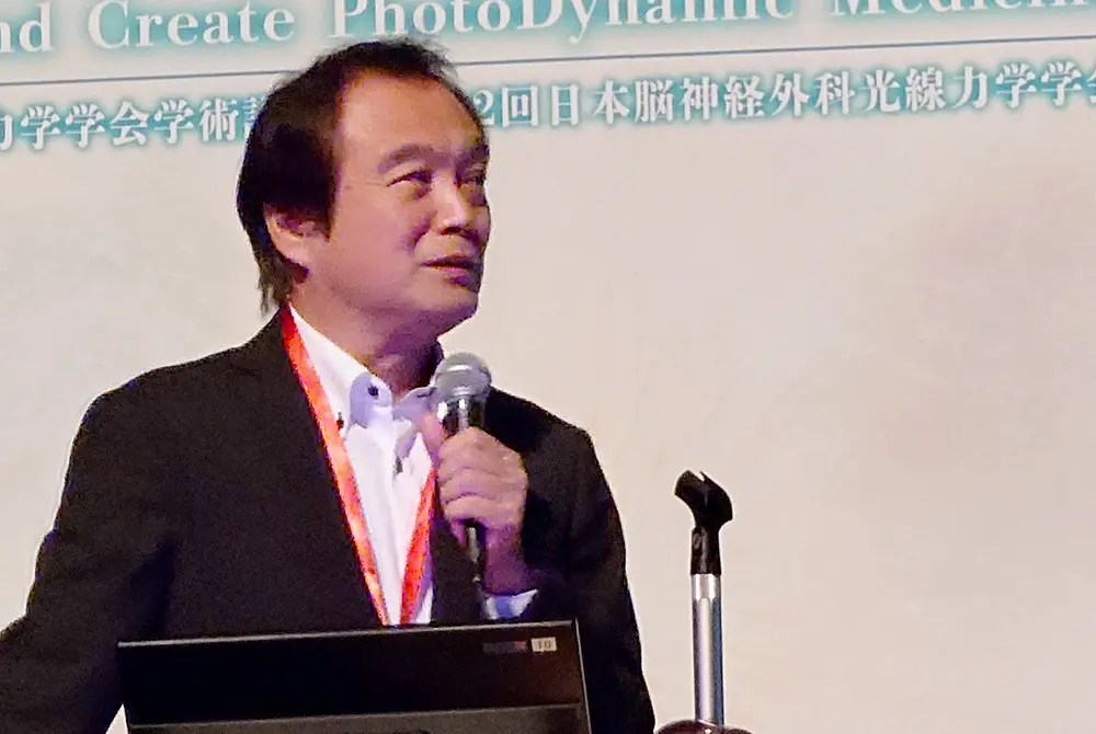 演台に立ち、マイクを持って講演する小倉俊一郎氏。