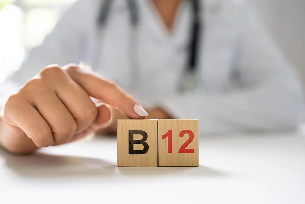 医療従事者の前に、ビタミンB12を示す木製ブロックが置かれている様子。