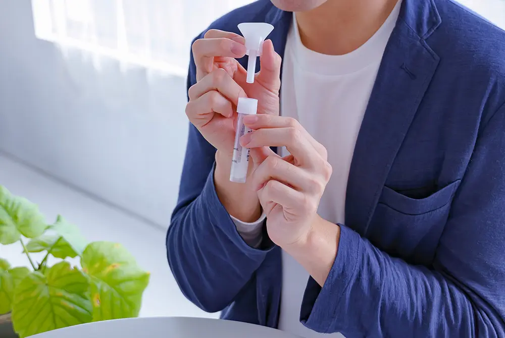 男性が検査用の容器を持ち、唾液を採取しようとしている様子。