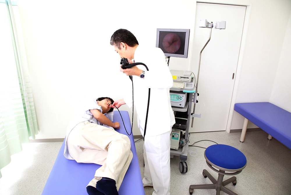診察室で、医師が内視鏡を使って患者の上部消化管を検査している様子。