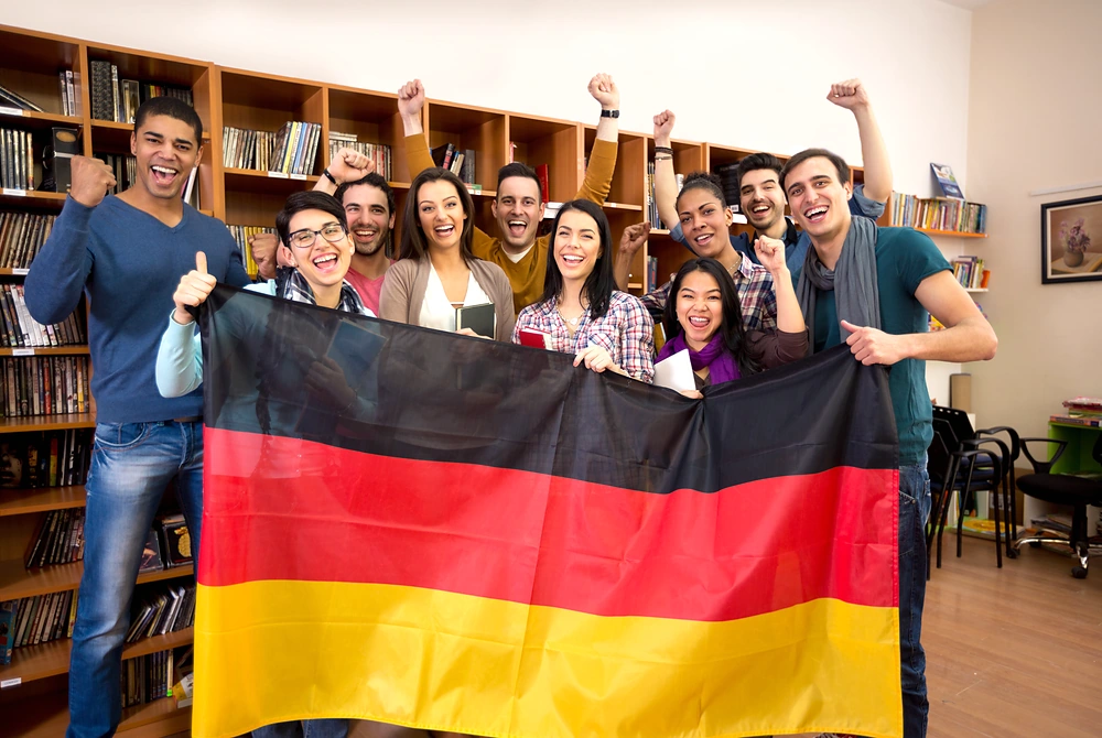 ドイツ国旗を持った若者たちが、笑顔で集まっている様子。