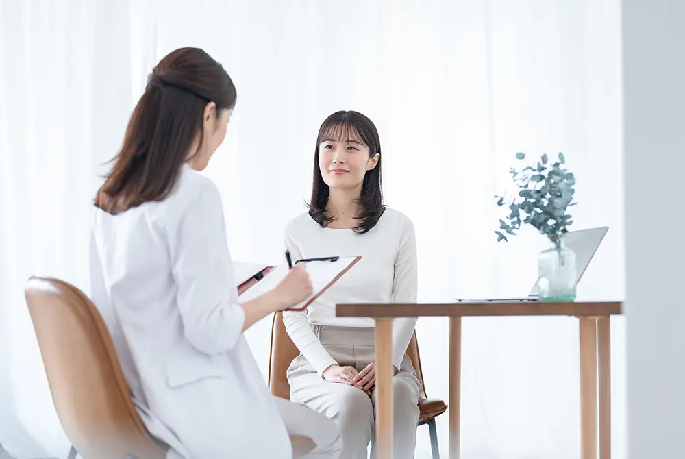 白衣を着た担当者が、女性と向き合って説明しているカウンセリングの様子。