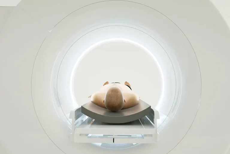 検査台に横たわる人が、CTまたはMRIの画像検査装置に入っている様子。