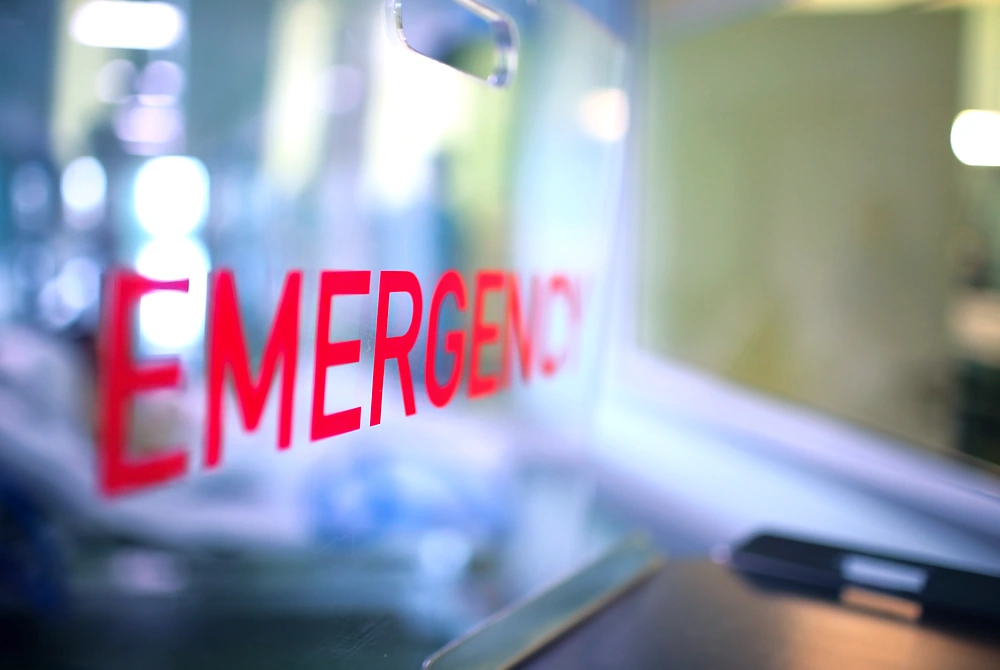 病院内の窓に「EMERGENCY」と書かれた救急部門の表示。