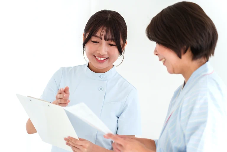 看護師が女性と一緒に資料を見ながら説明している様子。
