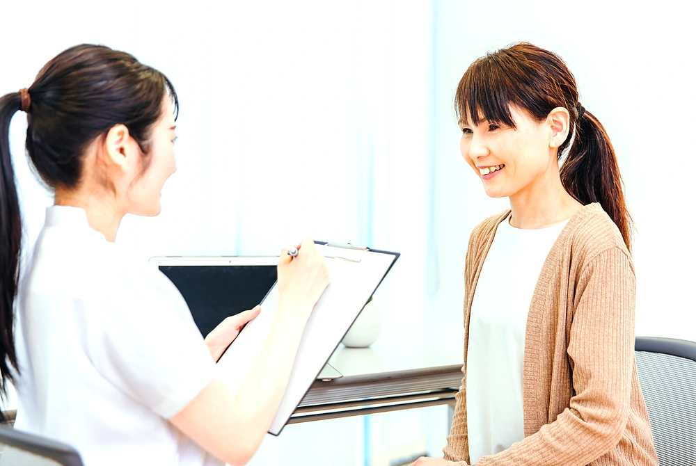医療者が女性に説明しながら、クリップボードに記入している様子。