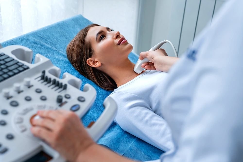 医療者が女性の首にプローブを当て、甲状腺の超音波検査を行っている様子。