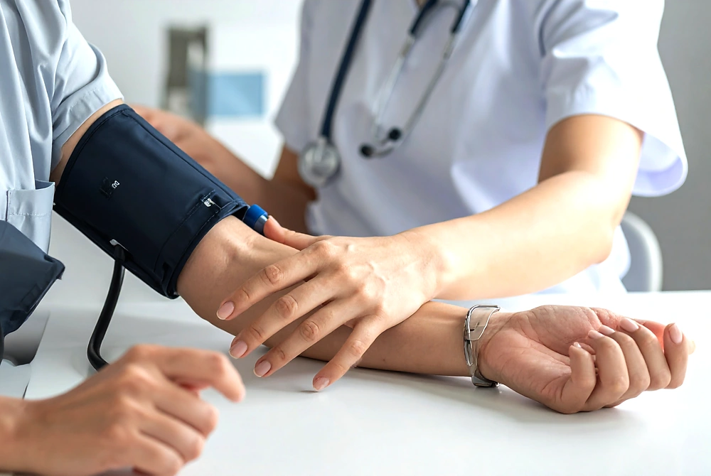 医療従事者が診察室で患者の腕にカフを巻き、血圧を測定している様子。