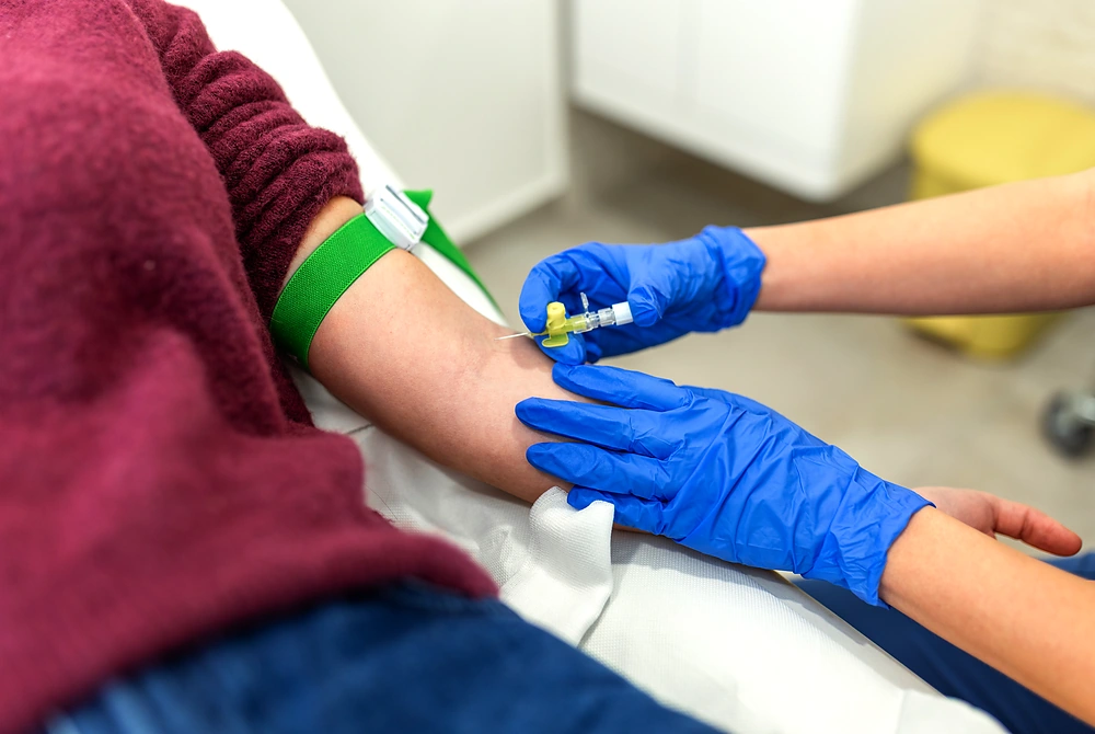 医療従事者が患者の腕から採血している様子。