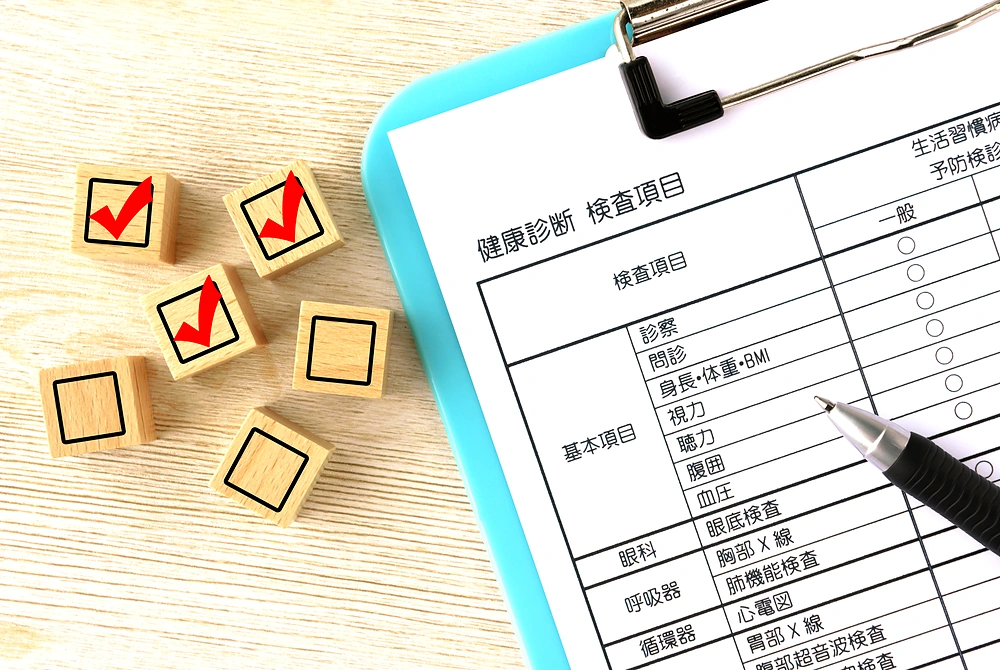 健康診断の検査項目表と、チェックマークが付いた木製ブロック。