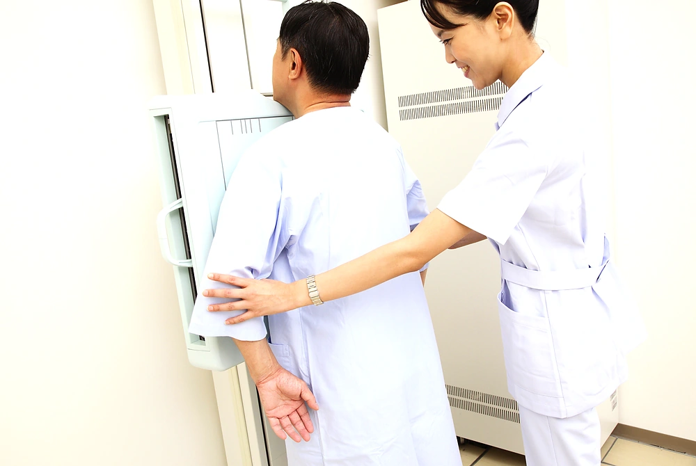 胸部X線検査で、医療従事者が受診者の姿勢を整えている様子。
