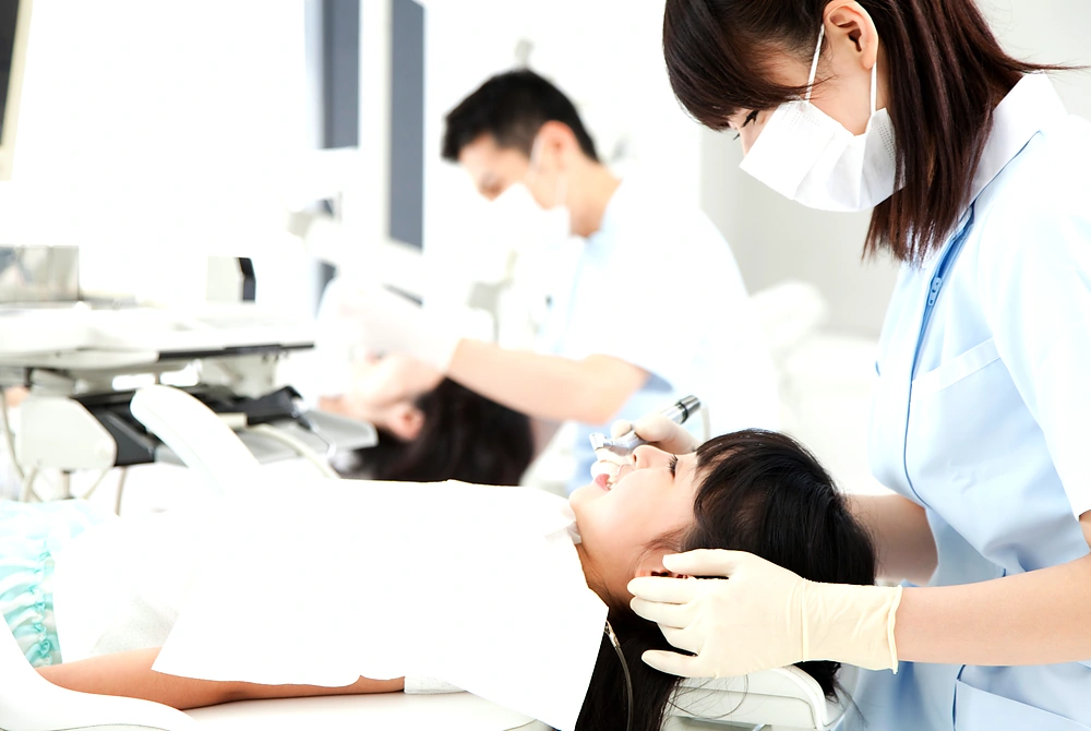 歯科医院で患者の口腔内を診察する歯科医療従事者たち。
